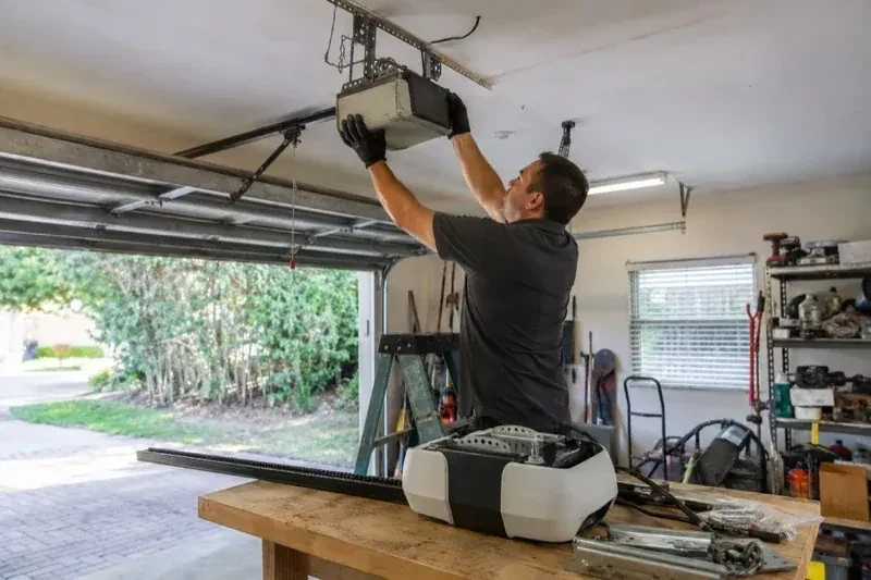 Person holding an overhead garage-door opener beside another opener and hardware on a workbench — Garage Door Opener Replacement, Vaughan