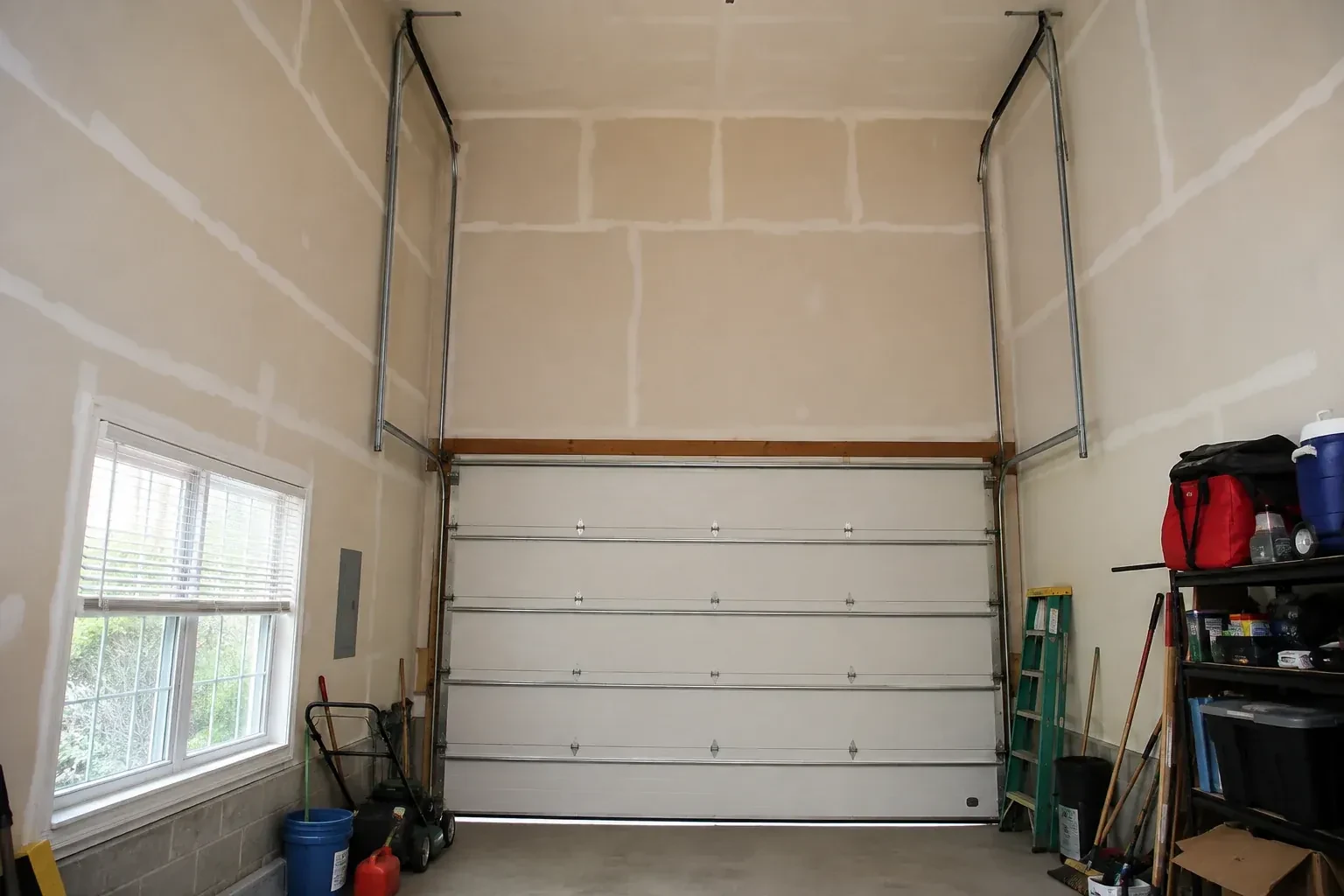Tall garage interior with a sectional door and tracks extending into overhead space. — High-Lift Garage Door Conversion, Vaughan
